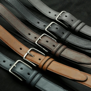 A variety of leather belts in different colors and styles, displayed on a dark background.